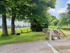 A rural landscape with a gravel path, a stone wall, and a swing set. - The Annex at Mains House (Tain)