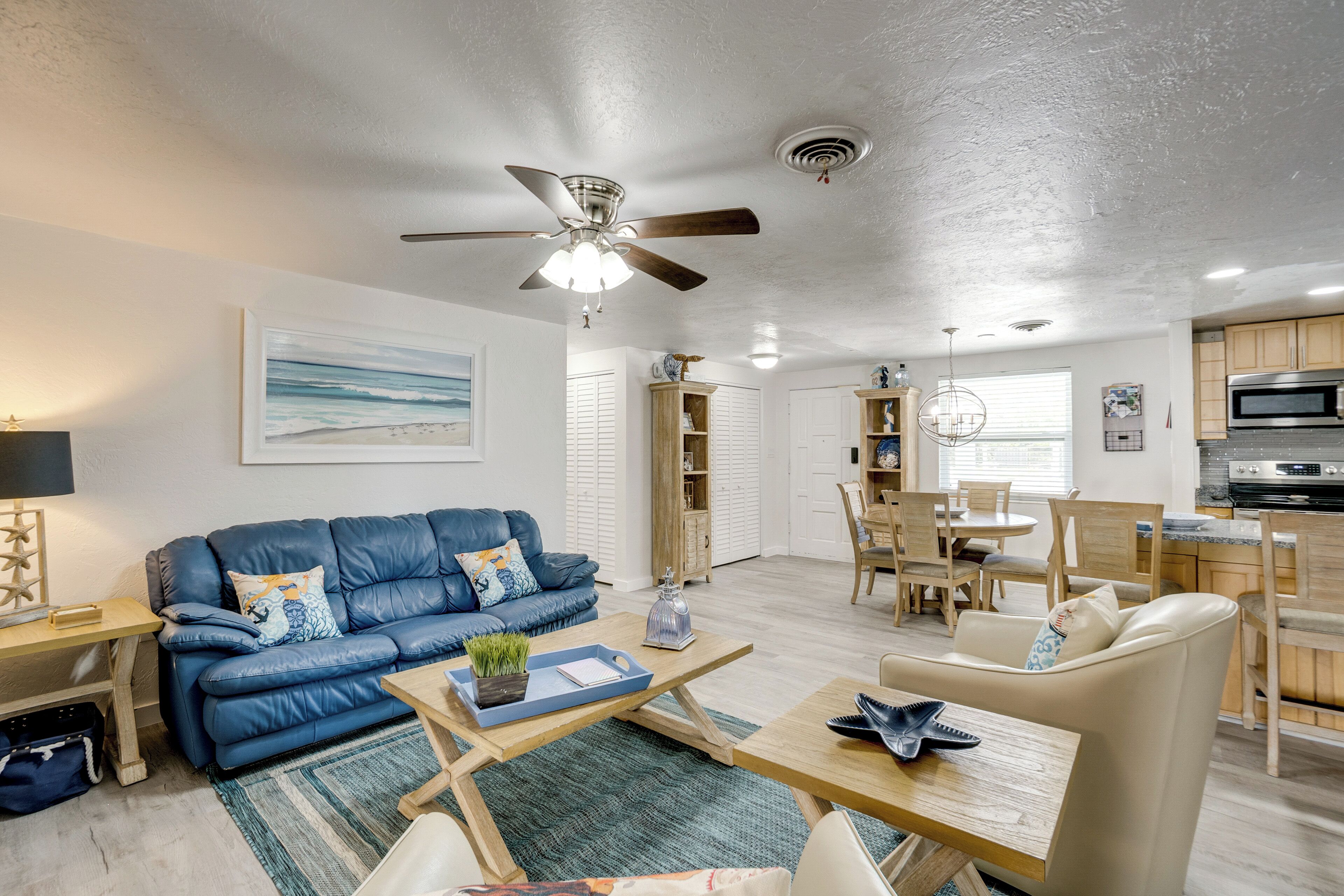 A modern living room with a blue leather sofa, a wooden coffee table, and a ceiling fan.