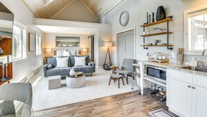 A spacious living area with a high ceiling, a cozy seating arrangement, a kitchen with white cabinetry, and a dining area. - Home w/ Lake Views on Finger Lakes Wine Trail (Penn Yan)