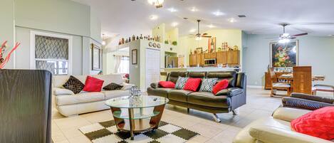 A spacious living room with a glass coffee table, leather sofas, and a dining area with wooden furniture.
