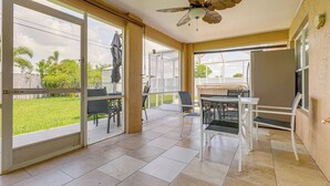 Un patio couvert doté d’un ventilateur de plafond, de portes-fenêtres coulissantes et d’une table avec des chaises.