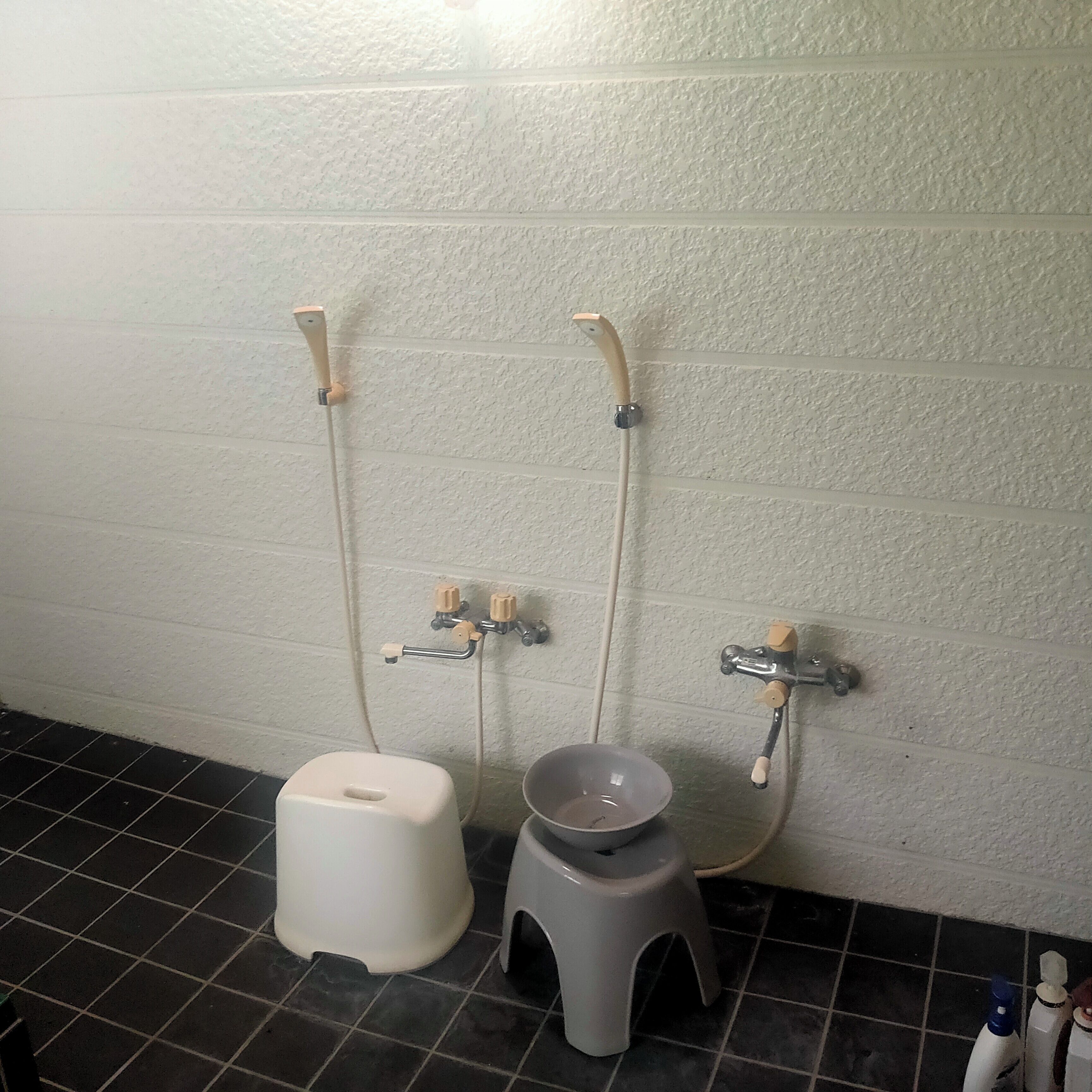 A bathroom with two toilets, a sink, and a wall-mounted faucet.