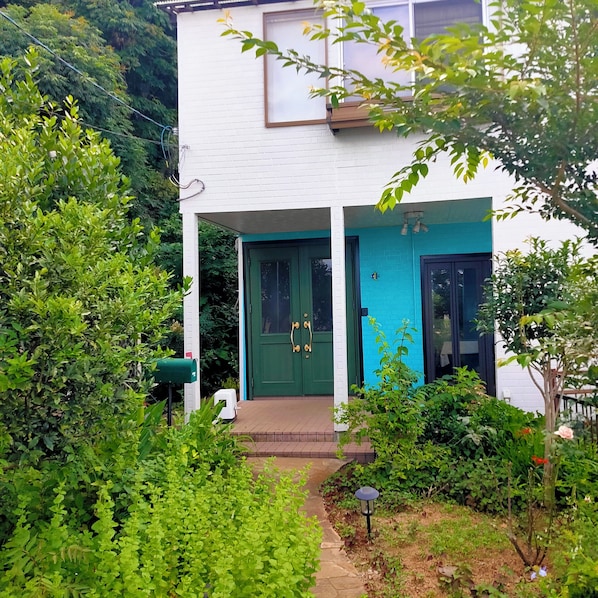 Un edificio blanco con una puerta verde y una pared azul de detalle.