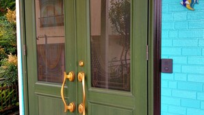 A green double door with a brass handle and a glass panel.