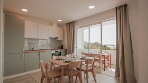 A modern kitchen with a dining area, large windows, and a view of the city.