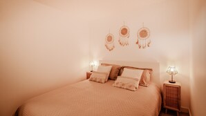 A bedroom with a bed, two bedside tables, and three wall-mounted dreamcatchers.