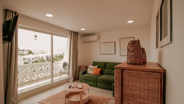 A living room with a green sofa, a wooden coffee table, and a wicker cabinet.