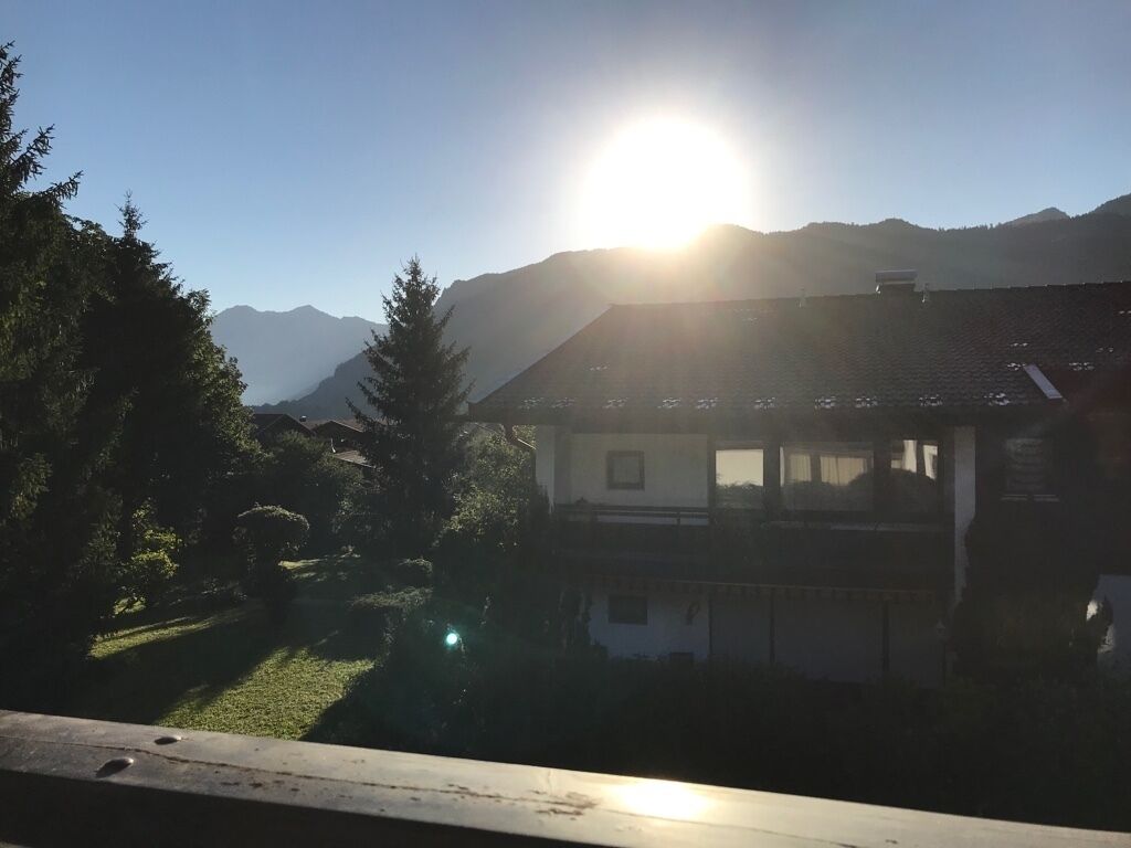 A house with a sloped roof, surrounded by trees and mountains.