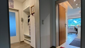 En hall med en dörr av trä, en klädhängare och utsikt över ett rum med ett stort fönster.