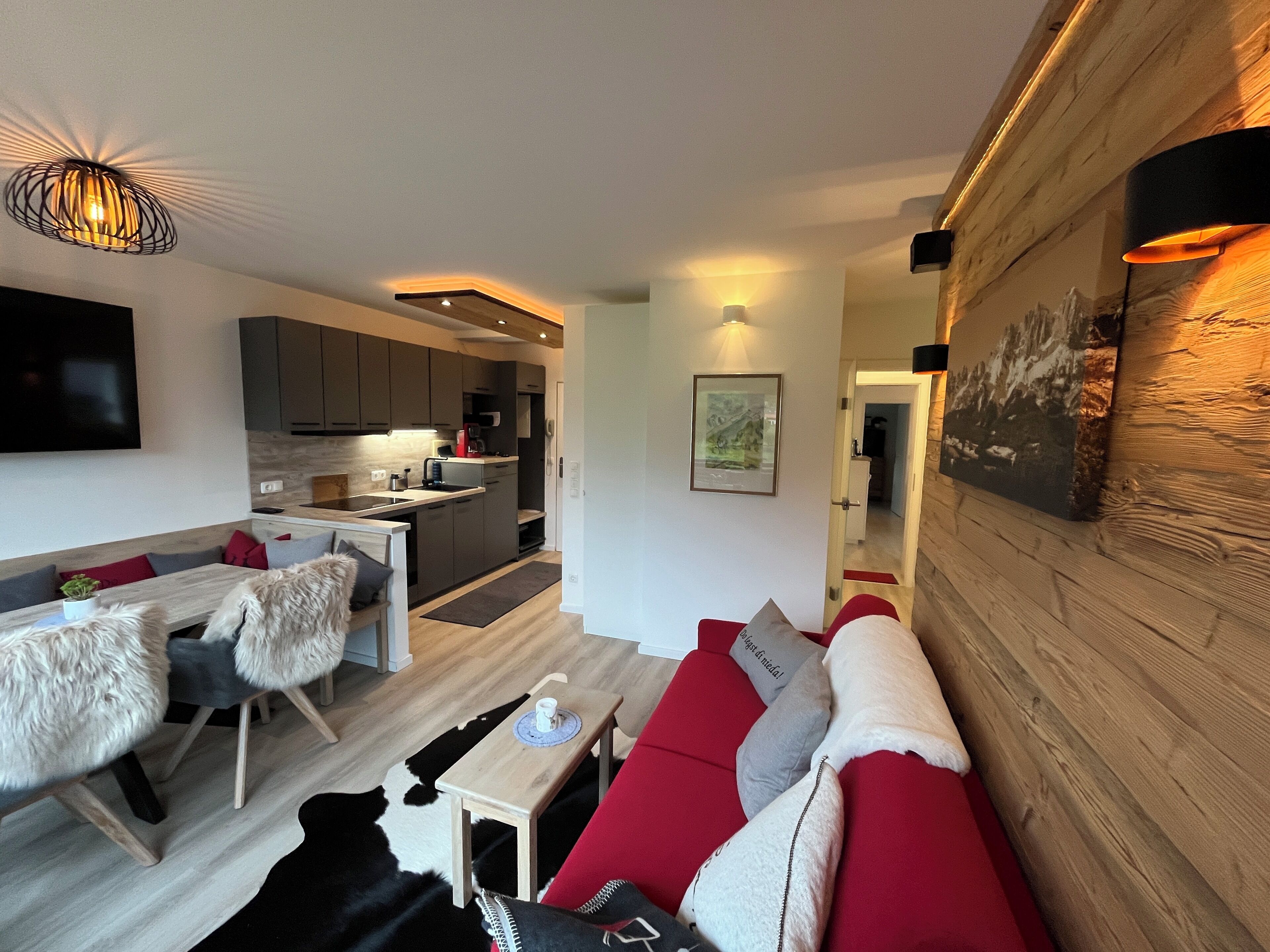 Una sala de estar moderna con un sofá rojo, una mesa de centro de madera y un comedor con una mesa y sillas blancas.