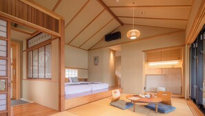 A traditional Japanese-style room with tatami flooring, a low wooden bed, a small table with tea set, and sliding doors.