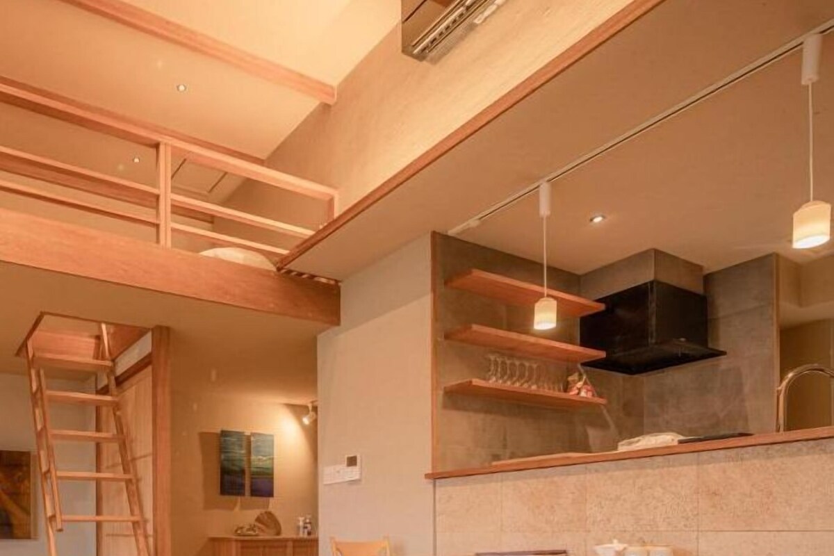 Un interno moderno con un letto a soppalco, un'area pranzo e una cucina.