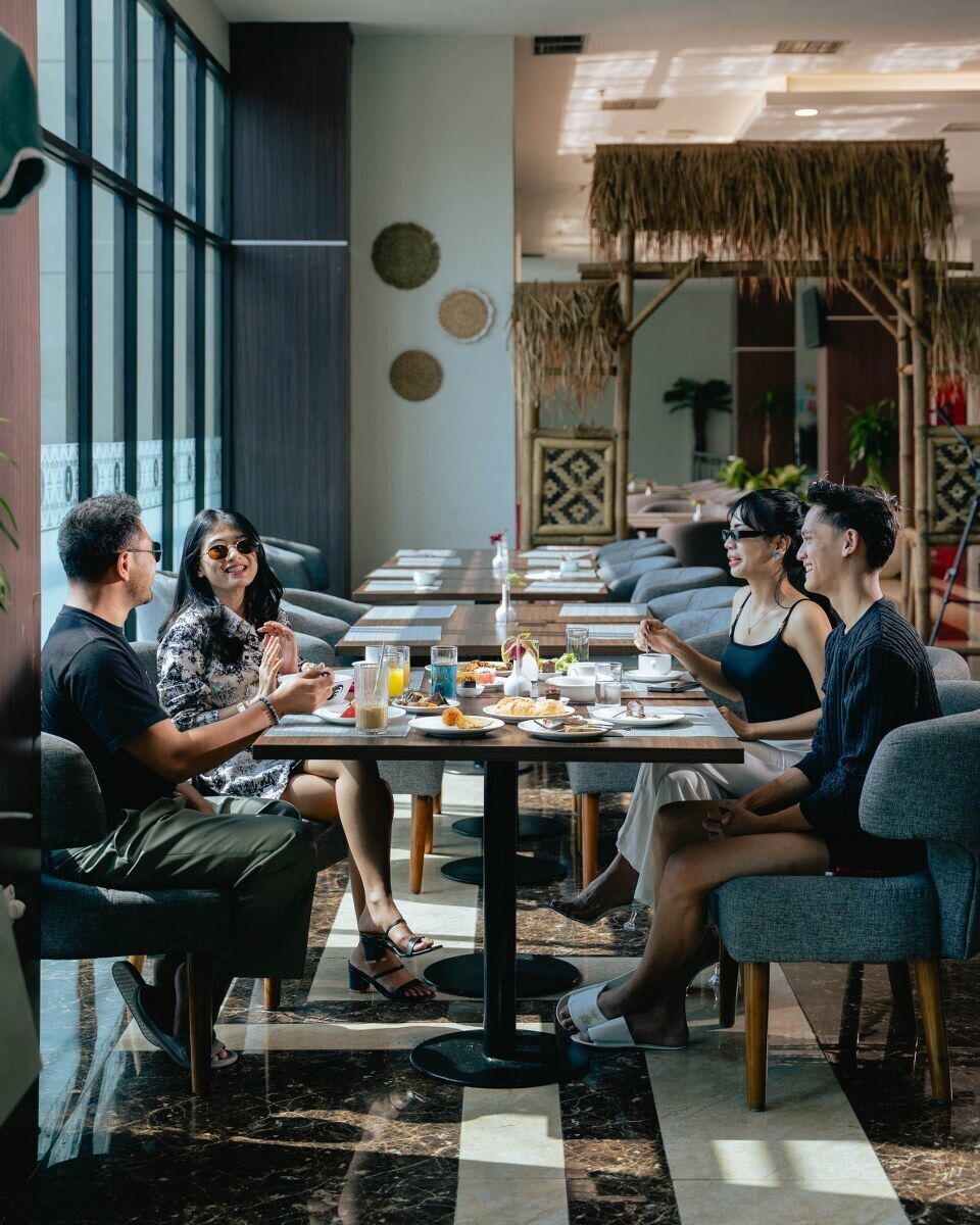 Un groupe de personnes est réuni dans un restaurant à l’intérieur moderne, avec notamment un mur décoré de motifs et un plafond en chaume.
