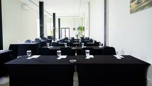 A conference room with tables and chairs, large windows, and a door at the far end. - Horison Ultima Sayaga Cibinong (Cibinong)