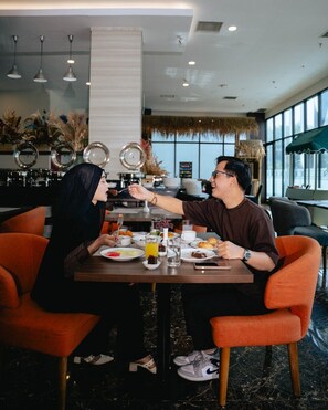 Un coin repas avec une table dressée pour deux personnes, où l’on propose une variété de plats et de boissons.