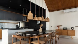 A modern kitchen with a central island, wooden chairs, and pendant lighting. - Makia Penthouse by Alfred in Bali (Canggu)