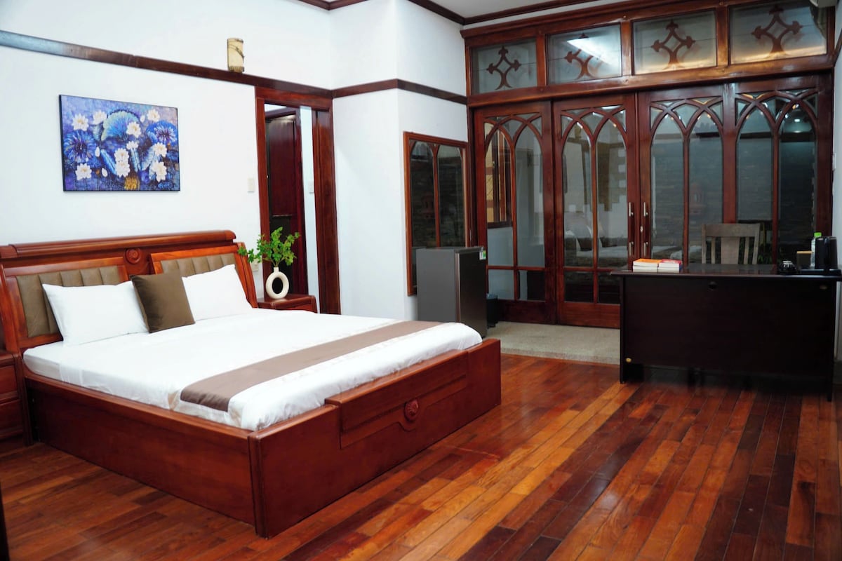 Un dormitorio con una cama de madera, un escritorio y un armario con puertas de cristal.