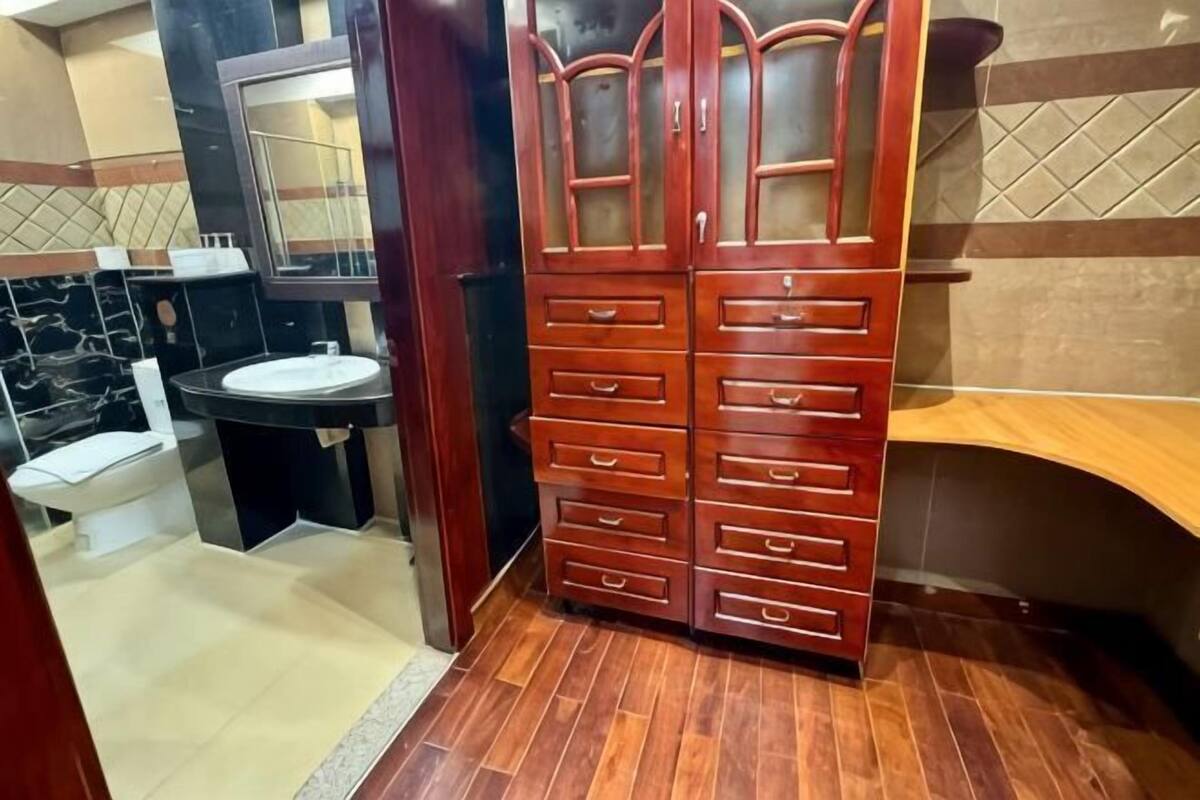 Een badkamer met een houten kastje, een wastafel en een spiegel.