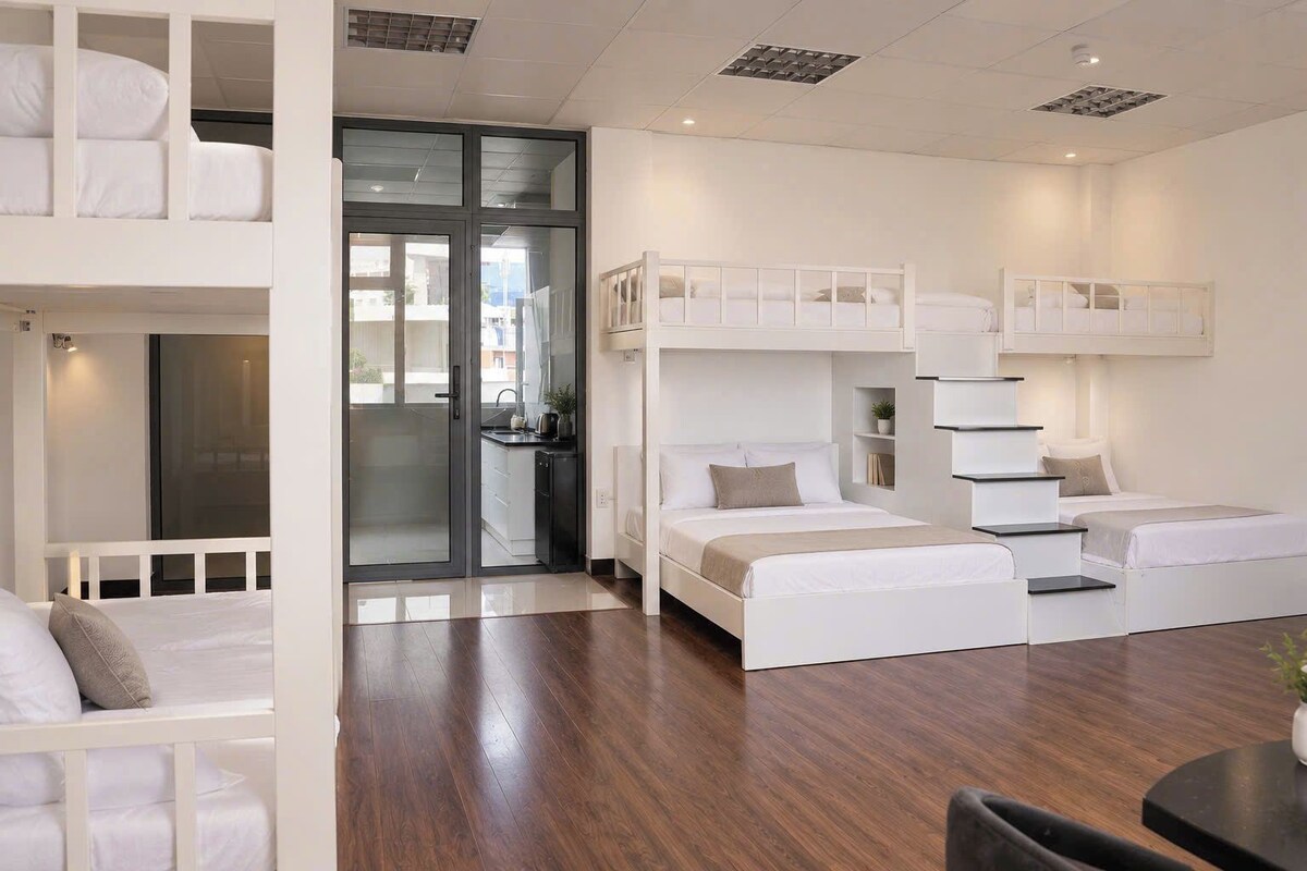 A compact hotel room with a bunk bed, a desk, and a small kitchenette.