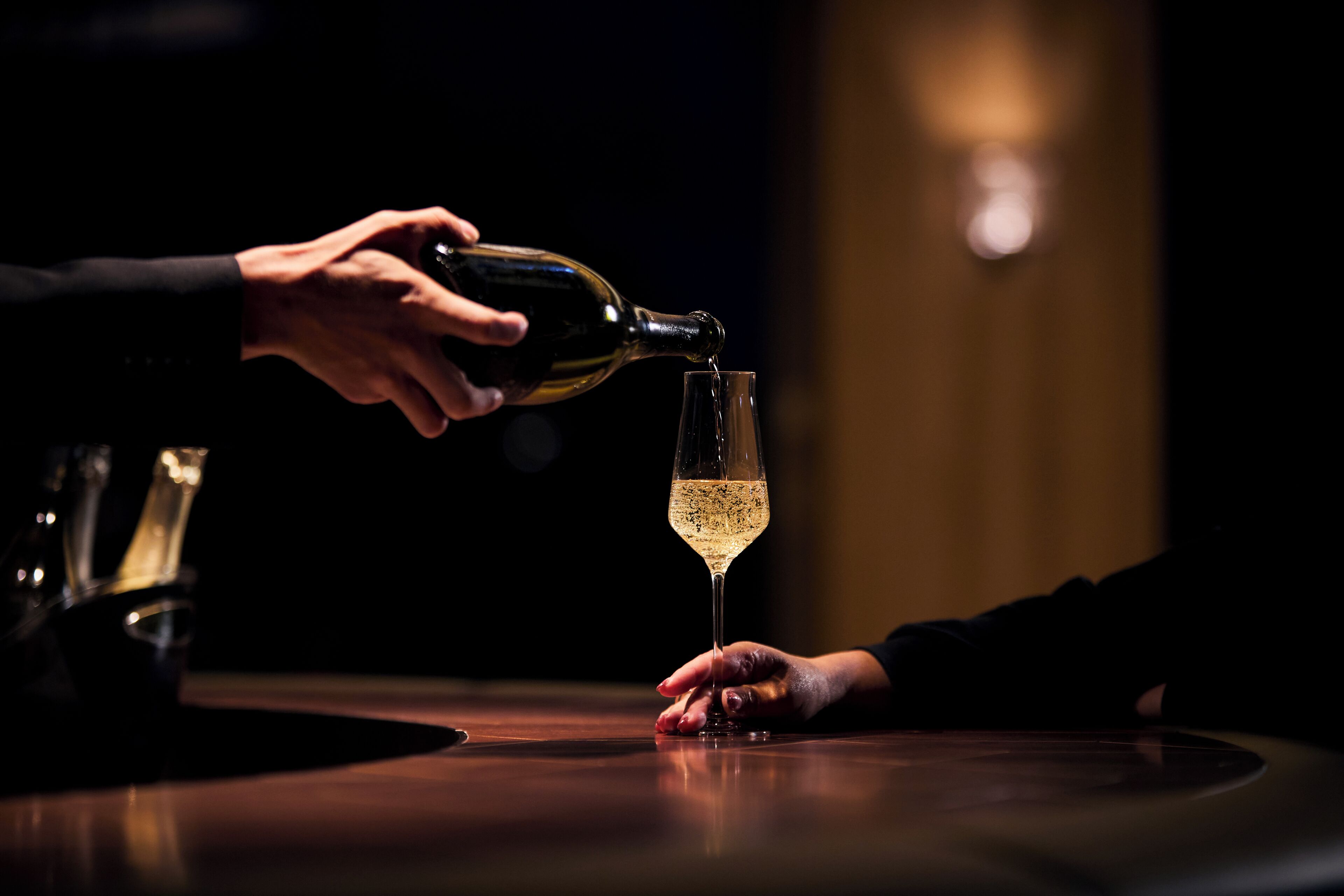 A hand pouring a drink into a glass.