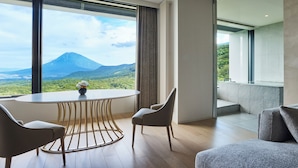 Una habitación moderna con una mesa redonda, dos sillas y vistas a una montaña.