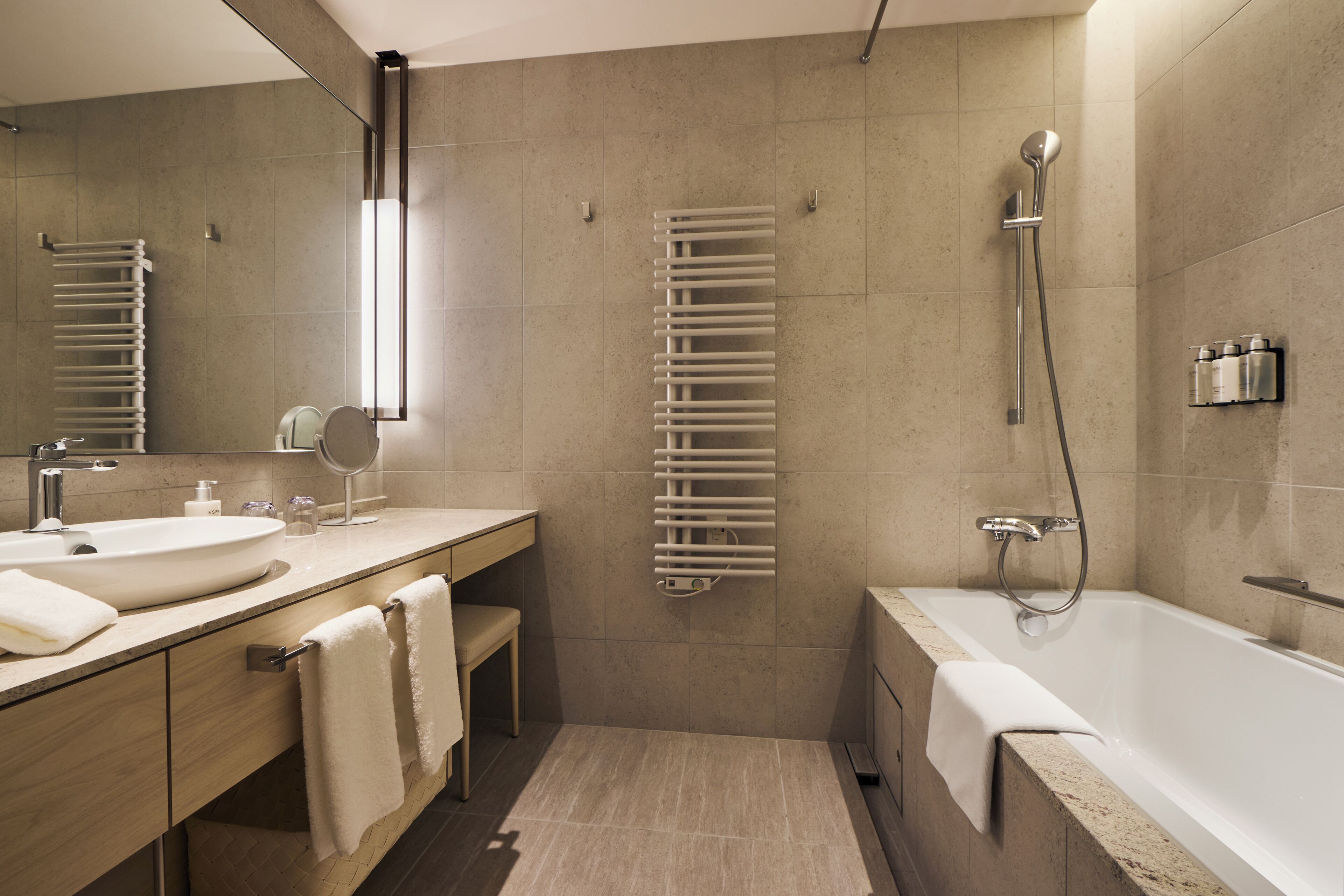 Een moderne badkamer met een ruime badkuip, een aparte douche, een ingebouwd wastafelmeubel en een handdoekhouder.