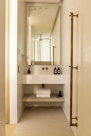 A modern bathroom with a white vanity, a large mirror, and a brass towel rack. - Luxurious Suite - AC- 2P- Madeleine/saint Honore (Paris)