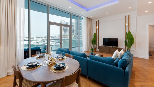 Een moderne woonkamer met een eethoek, grote ramen, een flatscreen-tv en uitzicht op de stad.
