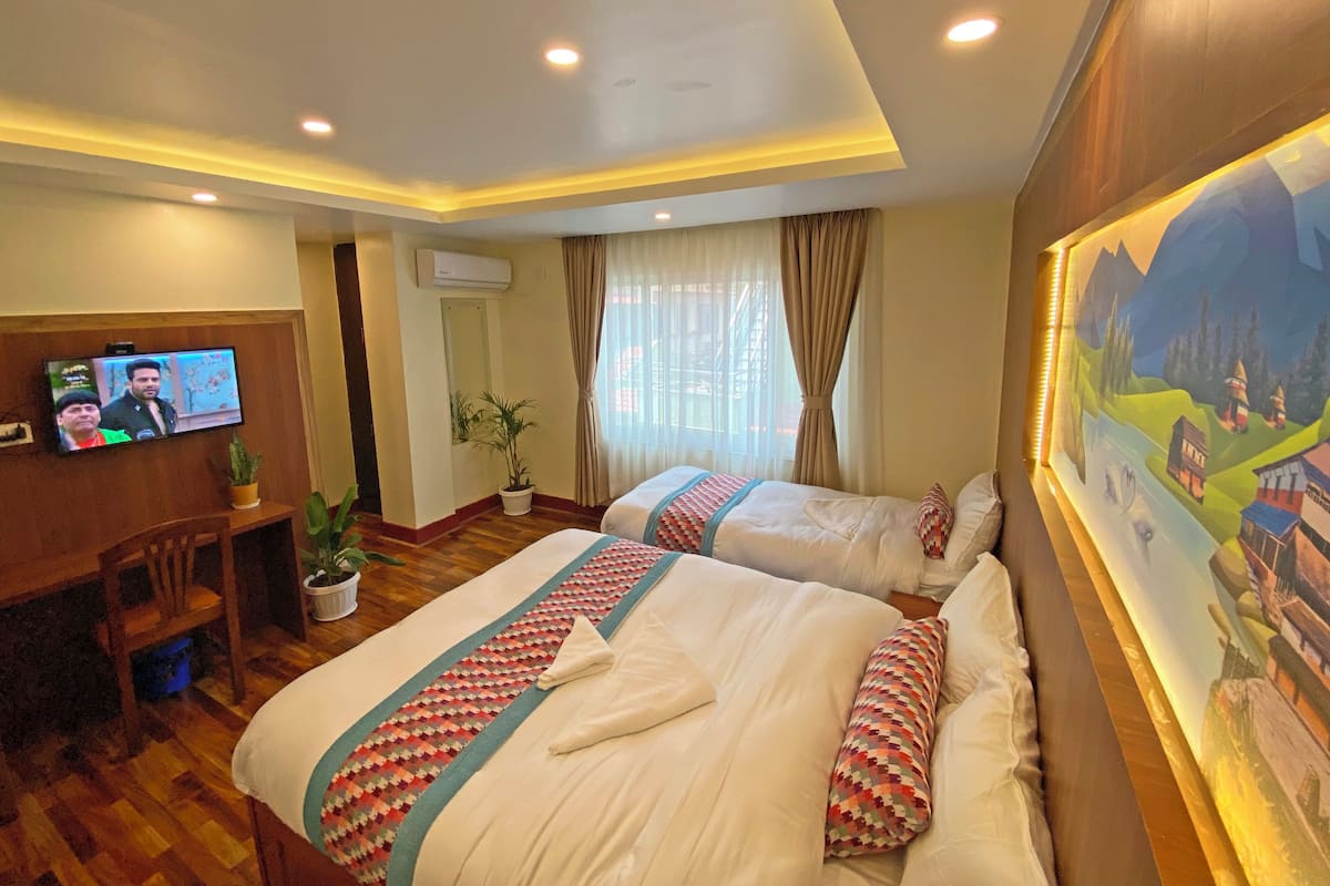 A hotel room with two beds, a TV, a desk, and a painting on the wall.