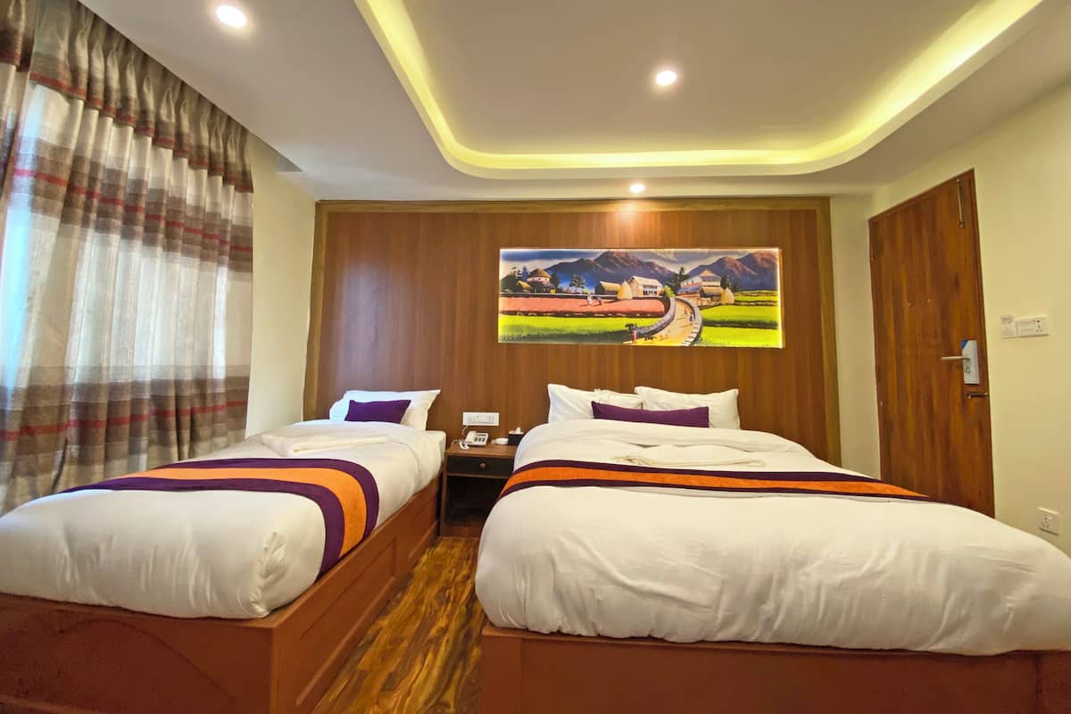 A hotel room with two beds, wooden flooring, a painting on the wall, and a curtain on the window.