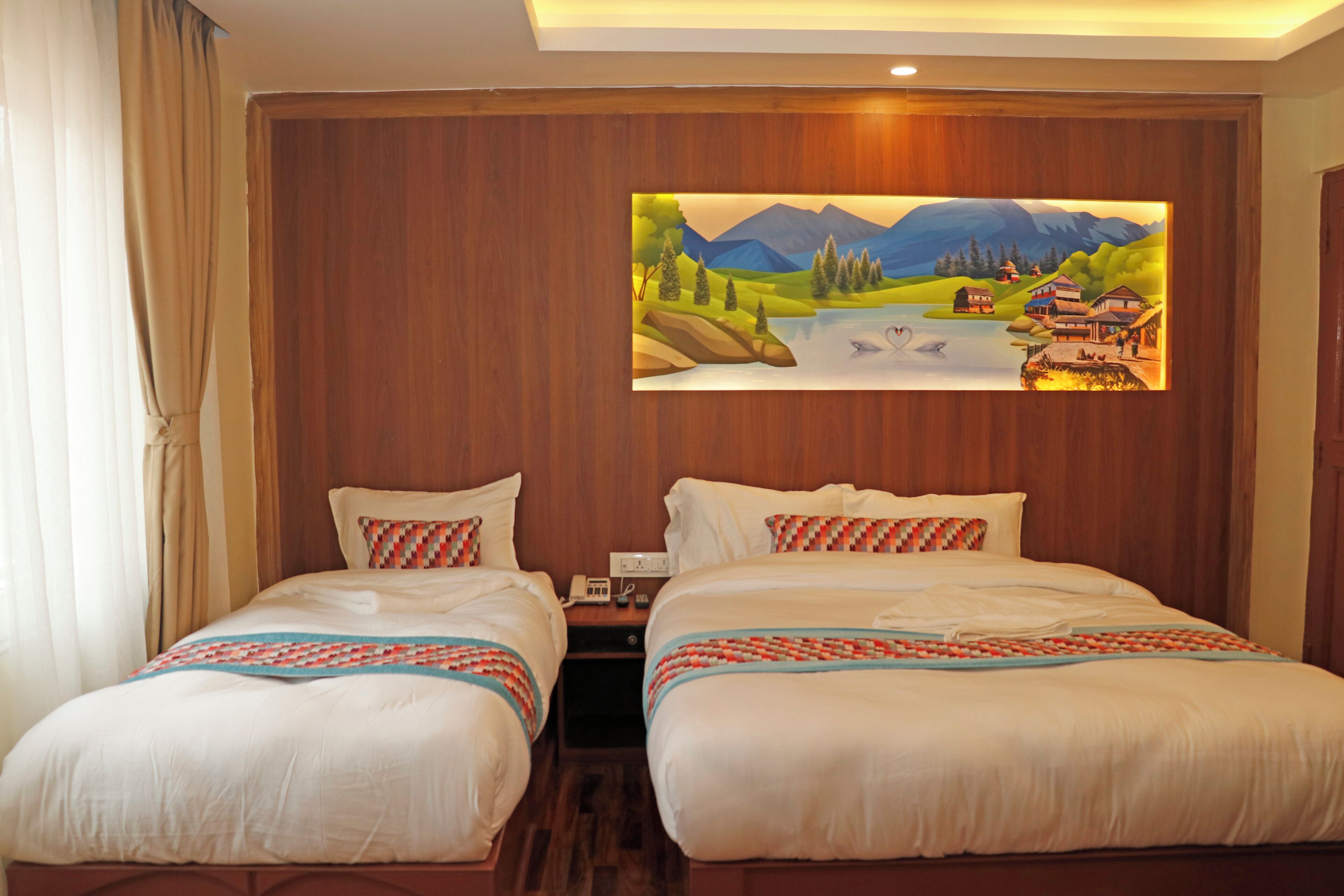 Een hotelkamer met twee bedden, een landschap op het wandpaneel en houten lambrisering.