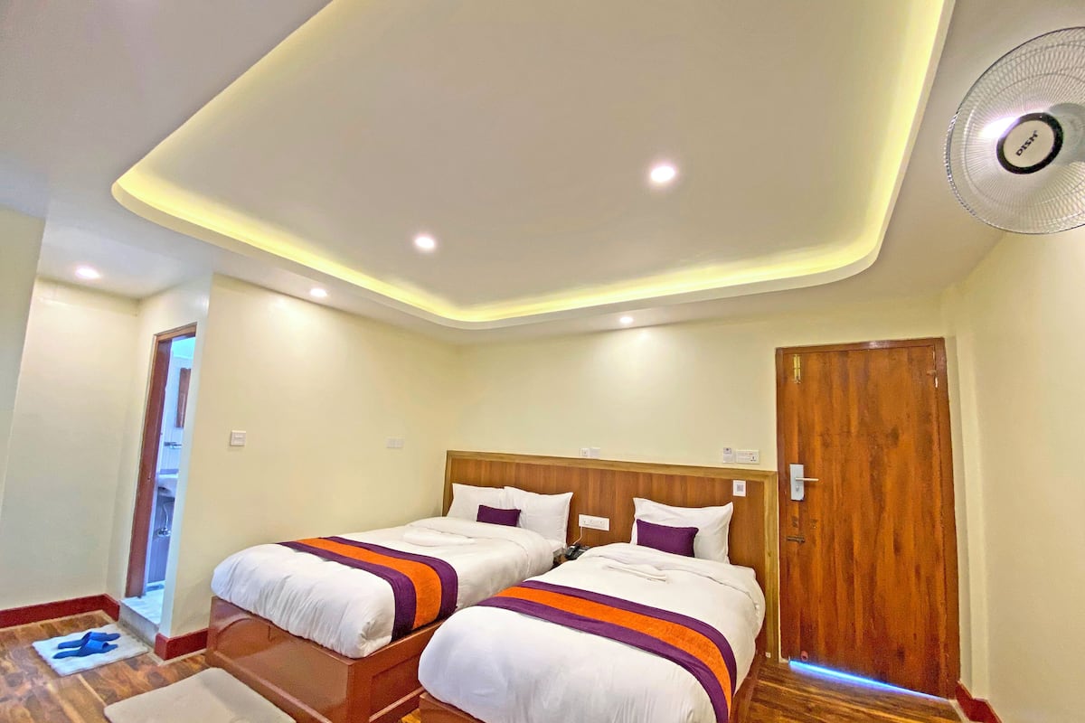 A hotel room with two beds, wooden headboards, and a ceiling fan.