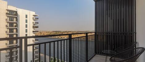 A balcony with a view of a river, a pool, and adjacent buildings.