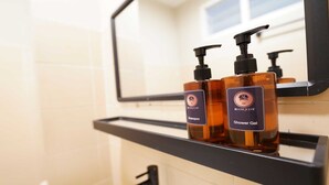 Baño con estante negro que contiene dos botellas de gel de ducha y champú.
