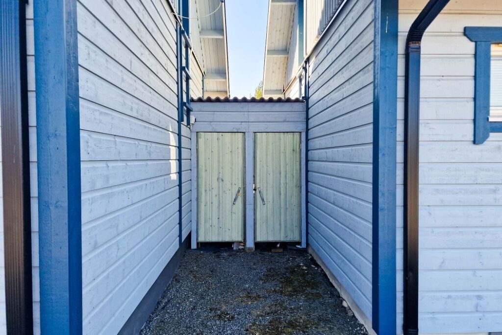 A narrow alleyway with a gravel path leading to a set of double doors.