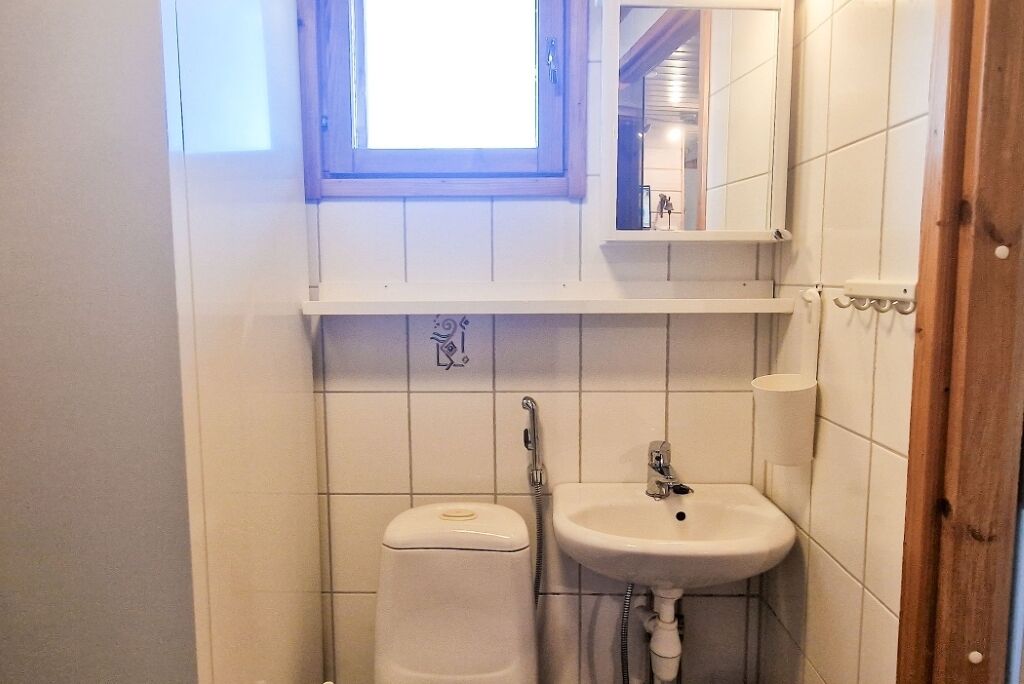 A small bathroom with a toilet, sink, and a window above the sink.