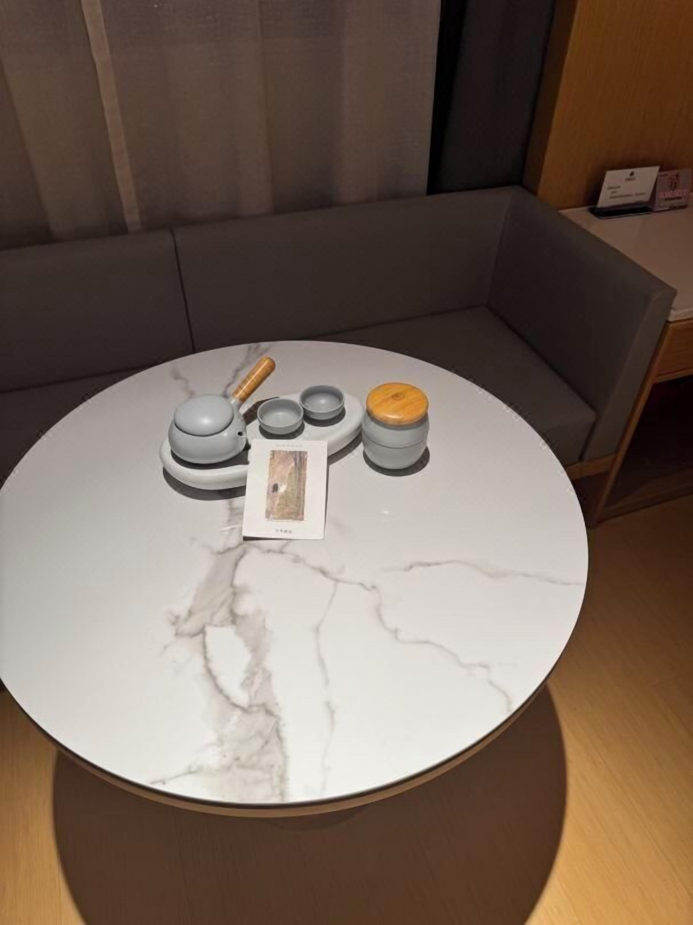 A round marble table with a small set of kitchen utensils and a card.