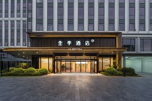Een hotelentree met een moderne gevel, grote glazen deuren en een bord met daarop de vermelding hotel.
