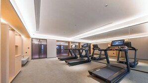 A modern hotel room with a treadmill, a large mirror, and a minimalist design. - Full Season Hotel-HGH (Hangzhou)