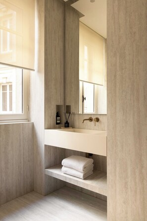 Ein modernes Badezimmer mit einem großen Fenster, einem weißen Waschbecken und einem Spiegel.