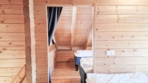 A narrow wooden room with a sloped ceiling, a bed, and a small table. - Villa Persikka, Himoslaakso Ski-in/out (Keski-Suomi)