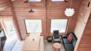 A cozy cabin interior with a wooden dining table, a sofa, and two chairs. - Villa Persikka, Himoslaakso Ski-in/out (Keski-Suomi)