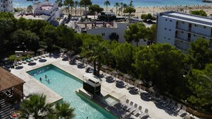 Um resort com piscina, cadeiras de sol e vista para o mar.