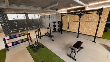 Un gimnasio con equipo de levantamiento de pesas, una banca y un estante para kettlebells.