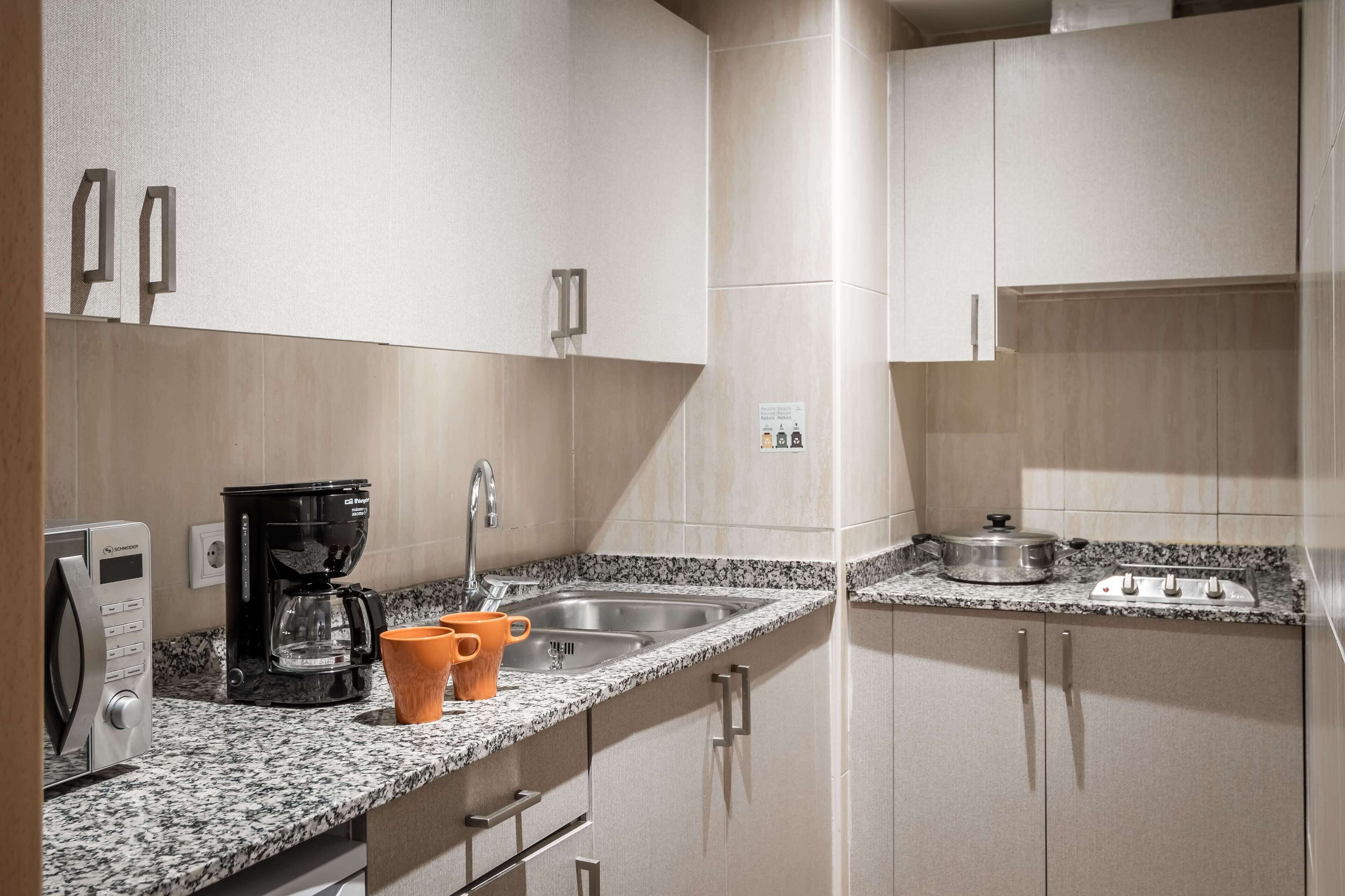 A modern kitchen with granite countertops, stainless steel appliances, and light-colored cabinetry.