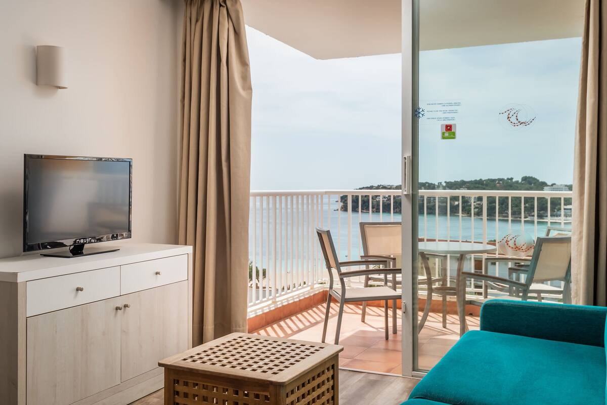 A balcony with a TV, a sofa, and a table with chairs.