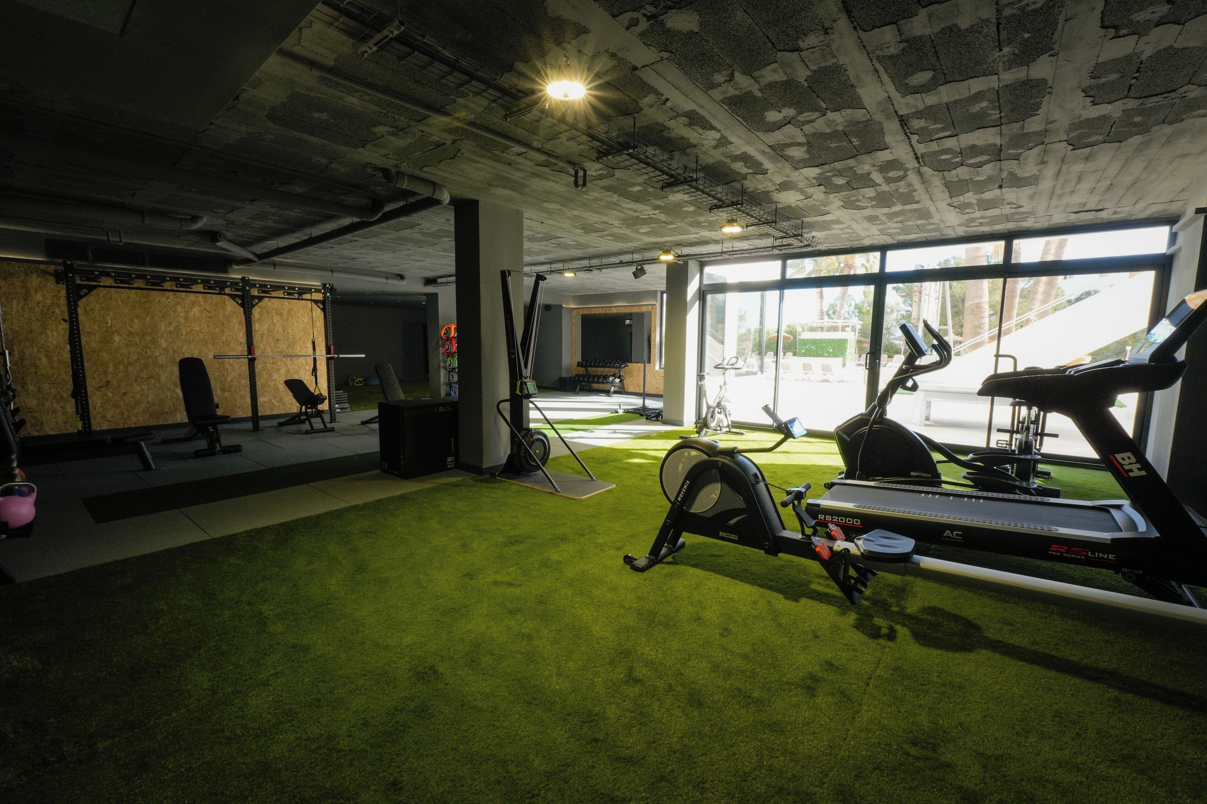 Un gimnasio con caminadora, bicicletas estáticas y equipo de levantamiento de pesas.