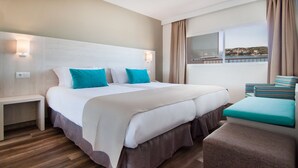Quarto de hotel com uma cama grande, mesa de cabeceira, uma cadeira e vista para o mar.