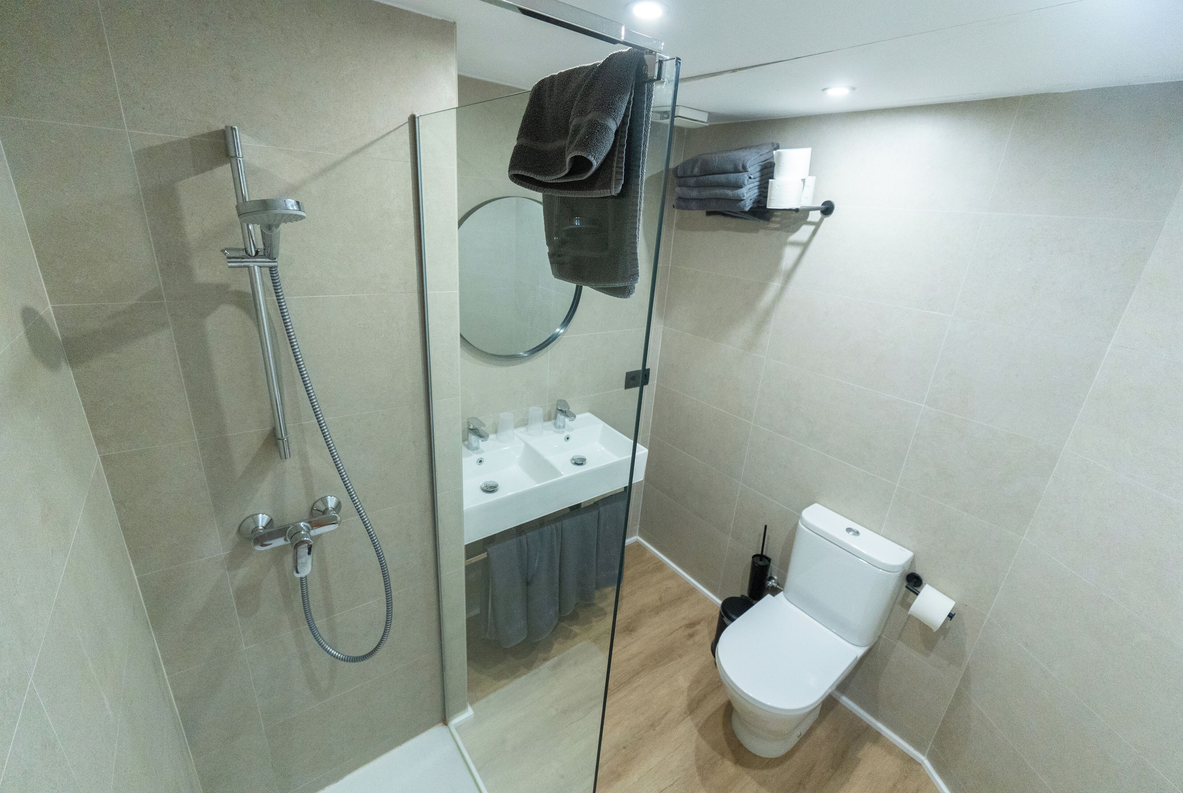 Een moderne badkamer met een douchecabine van glas, een toilet en een wastafel.