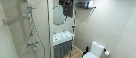 A modern bathroom with a glass-enclosed shower, a toilet, and a sink.